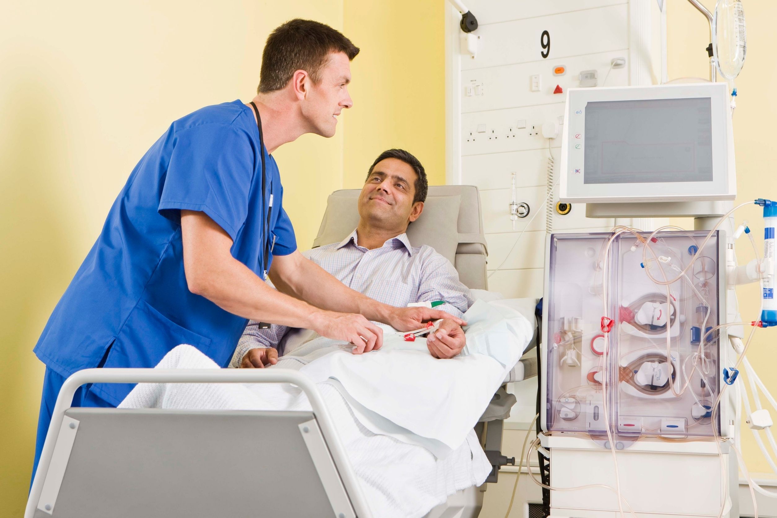 Dialysis nursing taking place in hospital while nurse provides treatment to patient