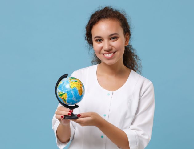 smiling travel nurse holding globe