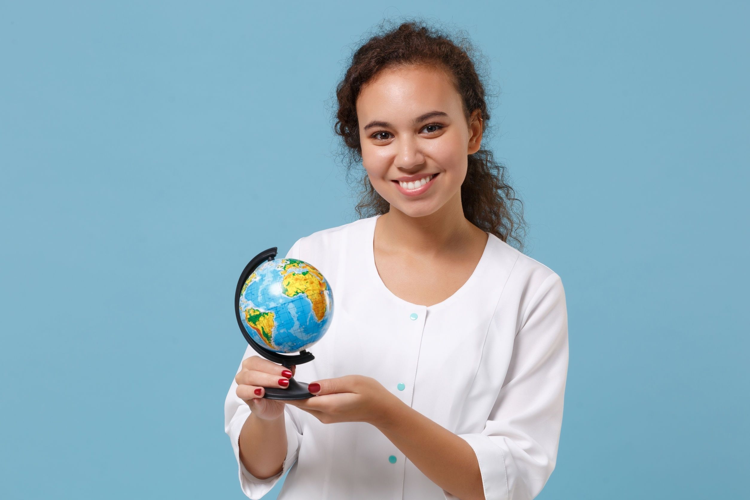 smiling travel nurse holding globe