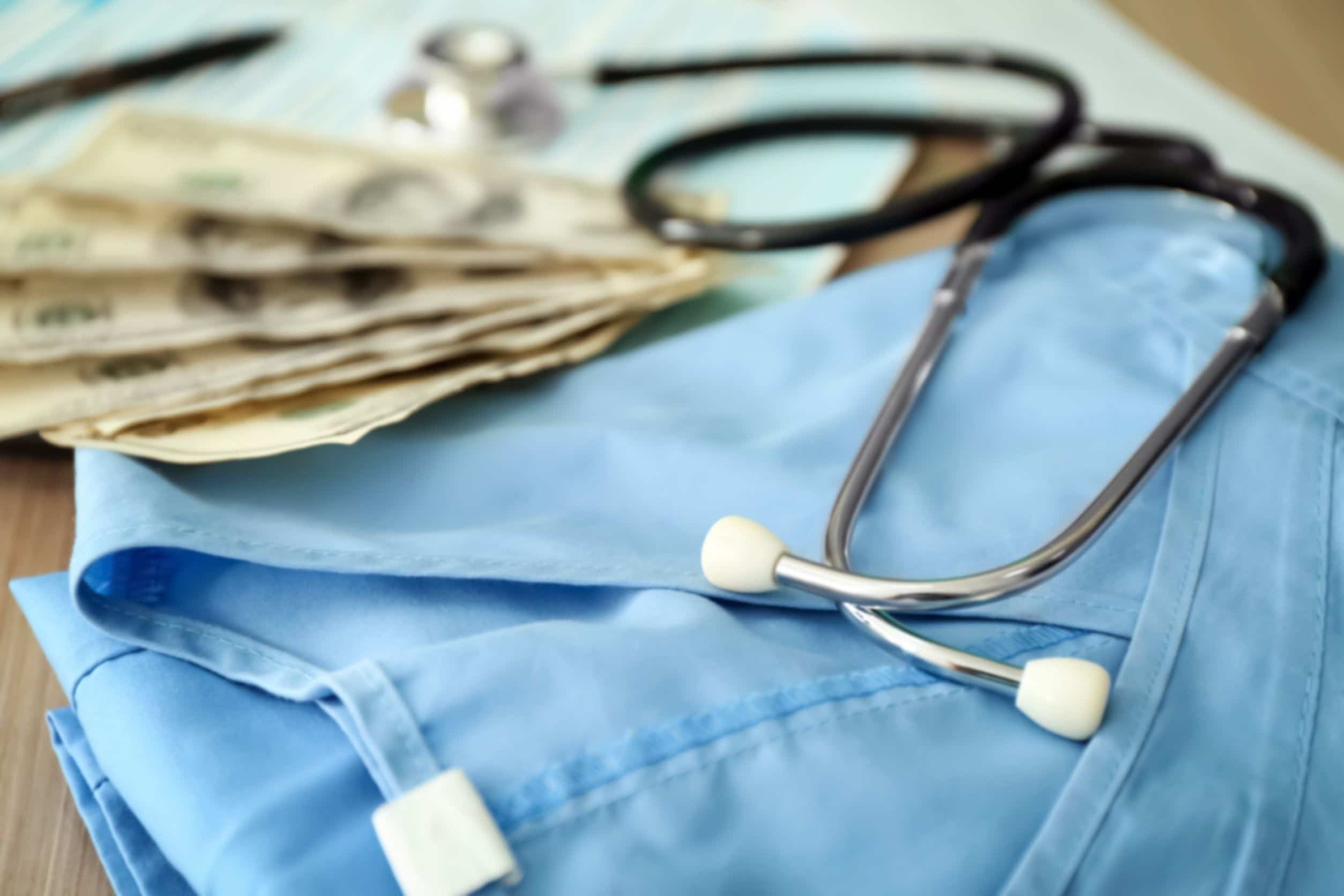 travel nurses uniform next to stethoscope and next to money